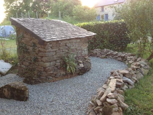 a stone building with a stone wall and rocks at La Vigne, La Ville Josse in Plessala