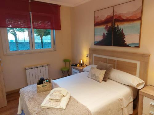 una camera con un letto bianco e due finestre di Apartamento Vieiro con plaza garaje gratis a Santiago de Compostela