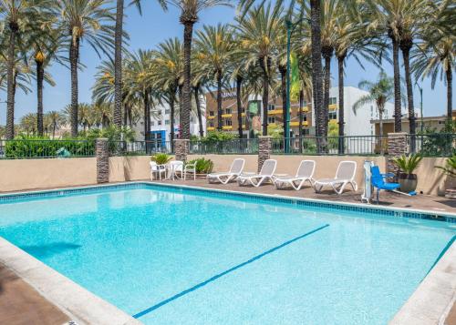 a swimming pool with chairs and palm trees at Anaheim Islander Inn and suites near Park and Convention center in Anaheim