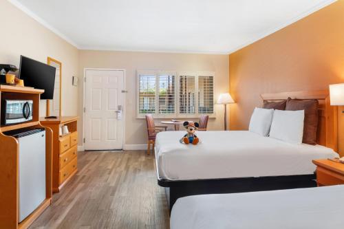 a hotel room with two beds and a teddy bear on the bed at Anaheim Islander Inn and suites near Park and Convention center in Anaheim