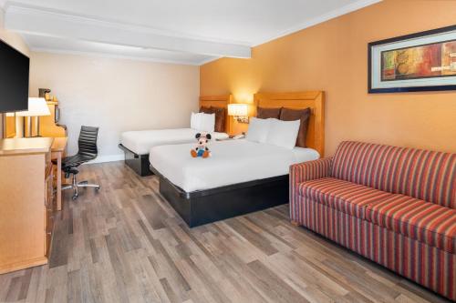 アナハイムにあるアナハイム アイランダー イン アンド スイーツのベッド2台とソファが備わるホテルルームです。