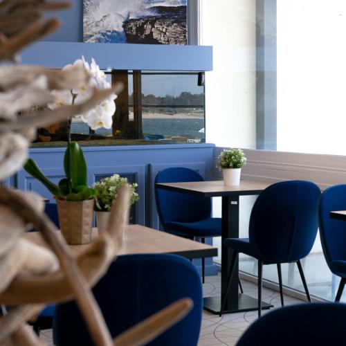 a dining room with blue chairs and a table at Logis Hôtel Le Calluna Restaurant La Flottille in Préfailles