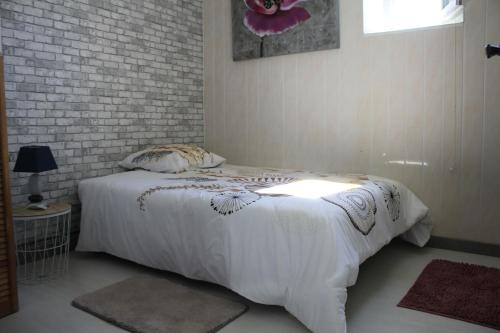 - une chambre avec un lit blanc et un mur en briques dans l'établissement App. 6 couchages 3 chambres Stationnement gratuit, à Béziers