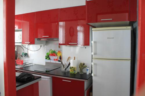 une cuisine avec des armoires rouges et un réfrigérateur blanc dans l'établissement App. 6 couchages 3 chambres Stationnement gratuit, à Béziers