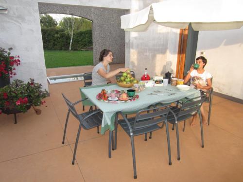 two people sitting around a table with a bowl of fruit at Aganis in Casarsa della Delizia