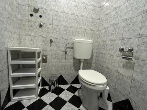 a bathroom with a toilet and a black and white floor at Pomerino Apartmans in Pomer