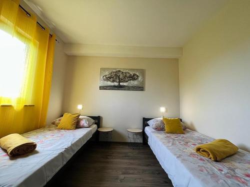 two beds in a room with yellow pillows on them at Pomerino Apartmans in Pomer