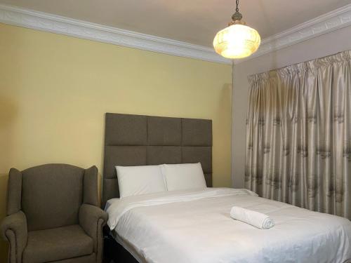 a bedroom with a large bed and a chair at CHIC Guest House & Solar system accommodations in Germiston