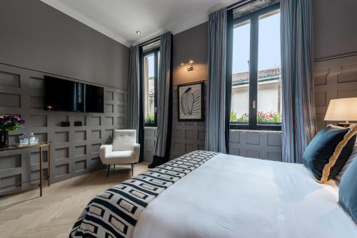 a bedroom with a bed and a tv and windows at The Couper Sant'Andrea in Milan