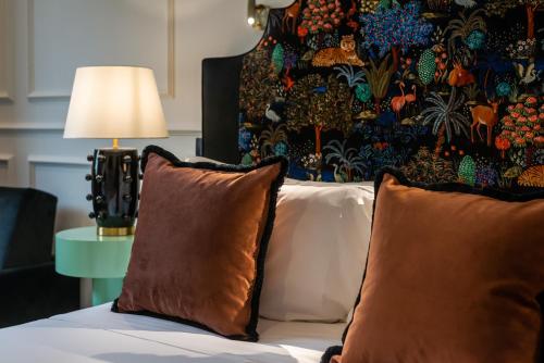 a bed with two brown pillows and a wall with at The Couper Sant'Andrea in Milan