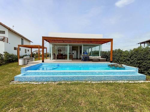 a swimming pool in front of a house at HOP ODAIBA exclusiva laguna y playa en Chincha in Chincha Baja
