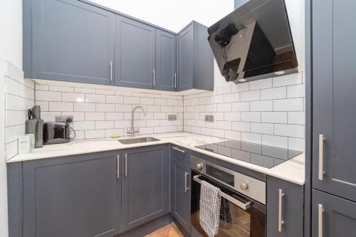 a kitchen with blue cabinets and a sink at NEW *SPACIOUS STUDIO *HIGH CEILING * MINS AWAY FROM BRIGHTON BEACH in Brighton & Hove