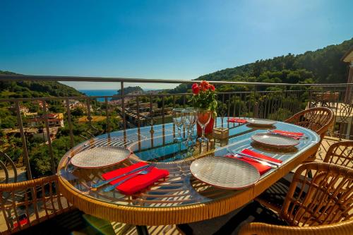 a glass table on a balcony with a view at Natura Luxury Suites Parga in Parga