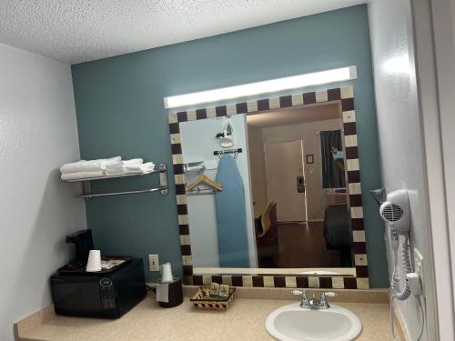 a mirror in a bathroom with a sink and a shower at Sunset Inn in Grants Pass