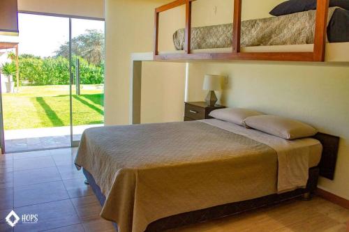 a bedroom with a bed and a large window at HOP OHANA exclusiva en campo y playa en Chincha in Chincha Baja