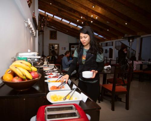 a woman standing at a buffet line with food at Hotel Kapac Inn-San Blas in Cusco