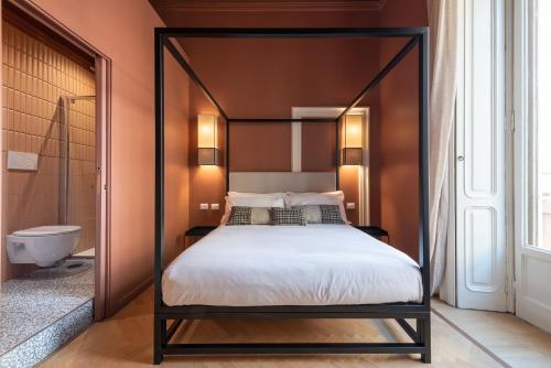 a bedroom with a canopy bed and a bathroom at The Couper Sant'Andrea in Milan
