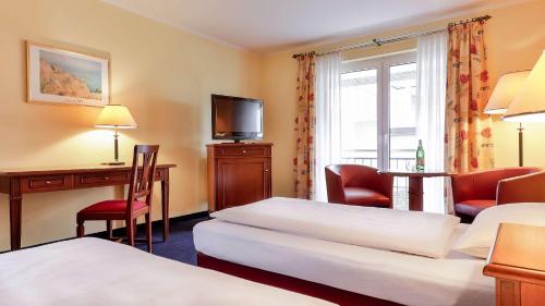 a hotel room with two beds and a desk at Dorint MARC AUREL Spa & Golf Resort in Bad Gögging