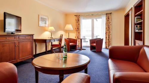 a hotel room with a couch and a table at Dorint MARC AUREL Spa & Golf Resort in Bad Gögging