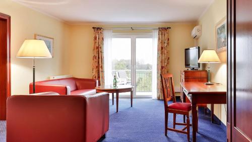 a room with a living room with a couch and a table at Dorint MARC AUREL Spa & Golf Resort in Bad Gögging