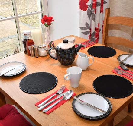 a wooden table with plates and utensils on it at The Rocks B&B in Crumlin