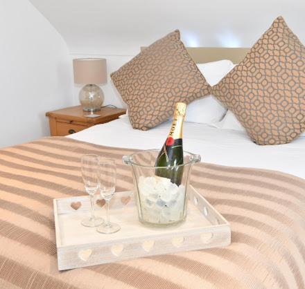 a tray with a bottle of champagne and two glasses on a bed at The Rocks B&B in Crumlin