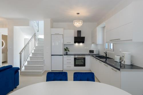 a kitchen with white cabinets and blue chairs at VILLA EKTAMA in Fiskardho