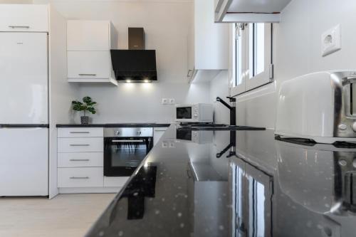 a kitchen with white cabinets and a black counter top at VILLA EKTAMA in Fiskardho