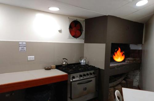 a kitchen with a stove and a fire in a fireplace at Hostería El Alemán in Cosquín