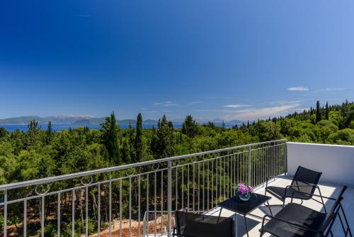 a balcony with chairs and a view of trees at VILLA EKTAMA in Fiskardho
