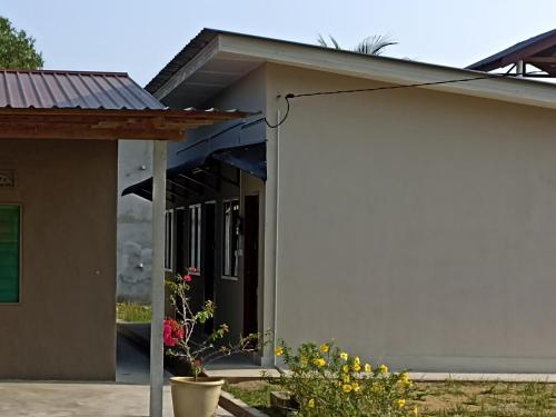 una casa blanca con una planta en un patio en Depulauserai Roomstays, en Pekan