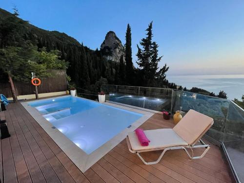 a swimming pool sitting on a deck with a chair and a chair at Casa Tramonto Beach View Agios Gordios Corfu in Agios Gordios