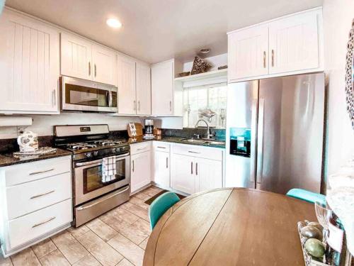a kitchen with white cabinets and a wooden table at Cozy beach home walking distance from ocean in Ventura