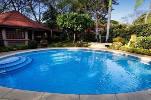 une grande piscine bleue en face d'une maison dans l'établissement Acacia Playa Hermosa, à Playa Hermosa