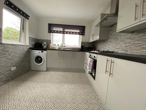 a kitchen with white cabinets and a washer and dryer at Pure Apartments Fife - Dunfermline West in Oakley