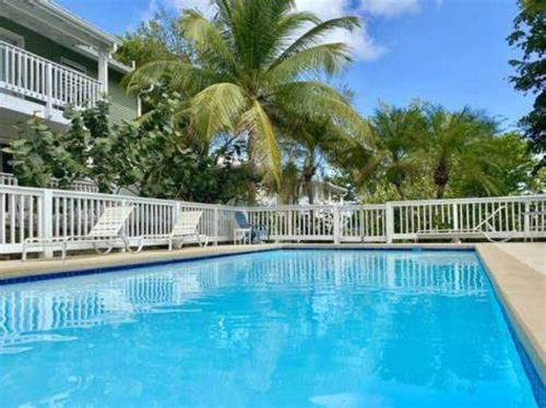 a swimming pool with a white fence and palm trees at Breezy Nights St. Croix in Christiansted