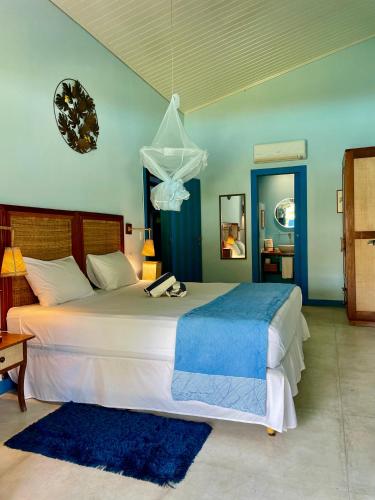 a bedroom with a large white bed with a blue blanket at Vila Stella Cadente in Fortim