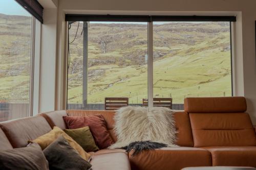 un sofá en una sala de estar con una gran ventana en Luxurious & Unique Villa / Nature / Beach / Hiking en Tjørnuvík