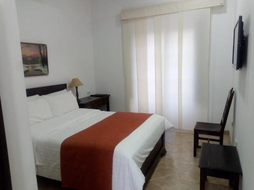 a hotel room with a bed and a chair at Hotel La Plazuela in Popayan