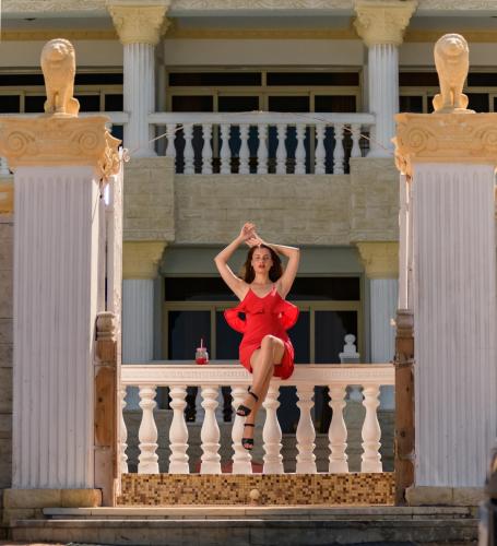 a woman in a red dress sitting on a balcony at Lucky palace Dahab in Dahab