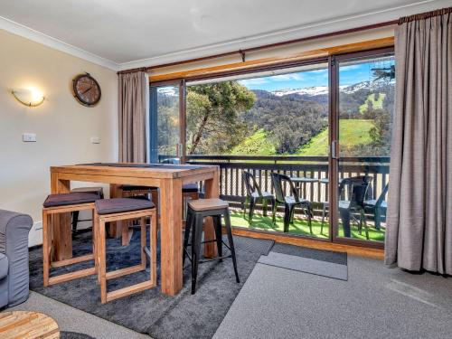 a living room with a table and chairs and a large window at Mowamba D3 in Thredbo