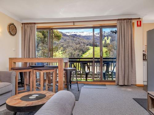 a living room with a table and a large window at Mowamba D3 in Thredbo