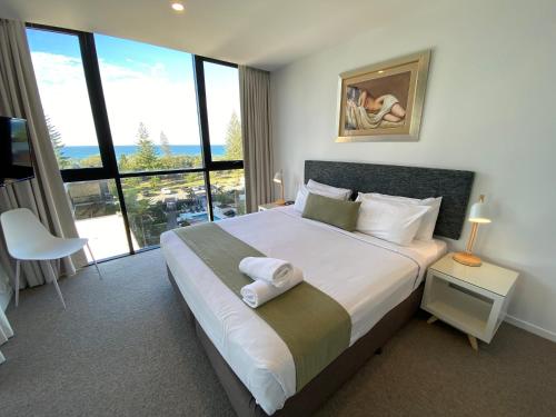 a bedroom with a large bed with a large window at Boardwalk Burleigh Beach - Official in Gold Coast