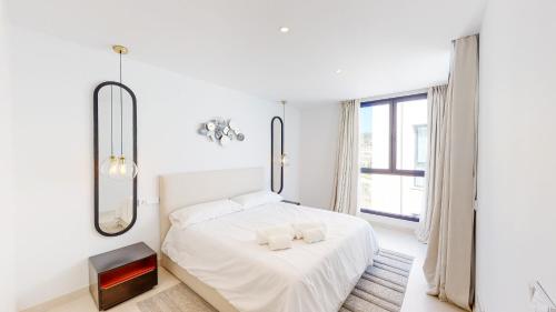 een witte slaapkamer met een bed en een spiegel bij Higueron West II - Luxury new built 3 bed apartmen in Fuengirola