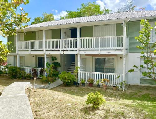 ein großes grünes Haus mit einer weißen Veranda in der Unterkunft Breezy Nights St. Croix in Christiansted