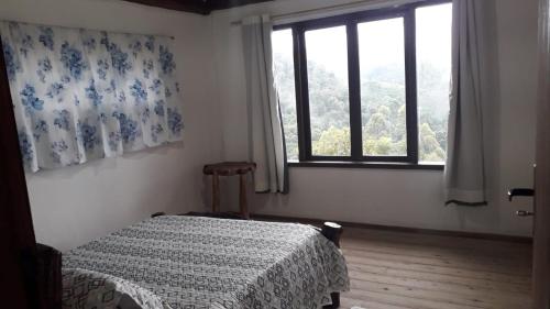 Schlafzimmer mit einem Bett und einem Fenster in der Unterkunft Chalé Sabiá in Aiuruoca