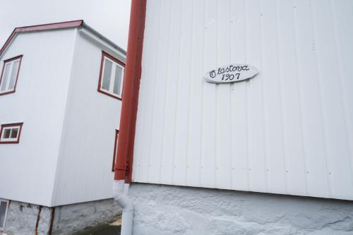 a white building with a sign on the side of it at 4 BR House / Scenic Village / Nature / Hiking in Við Gjógv