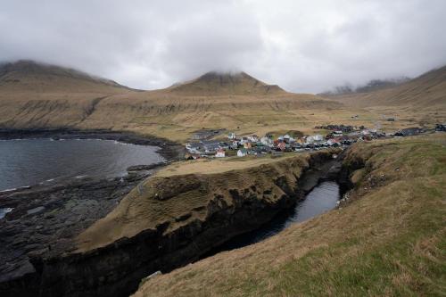 a group of houses on a hill next to a body of water at 4 BR House / Scenic Village / Nature / Hiking in Við Gjógv
