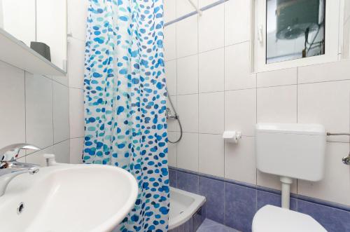 a bathroom with a sink and a toilet and a shower curtain at Apartments Ruzica M in Lopar