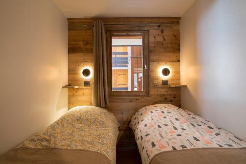 two beds in a small room with a window at Les Brigues - Appartement avec vue sur la montagne et accès aux pistes in Courchevel